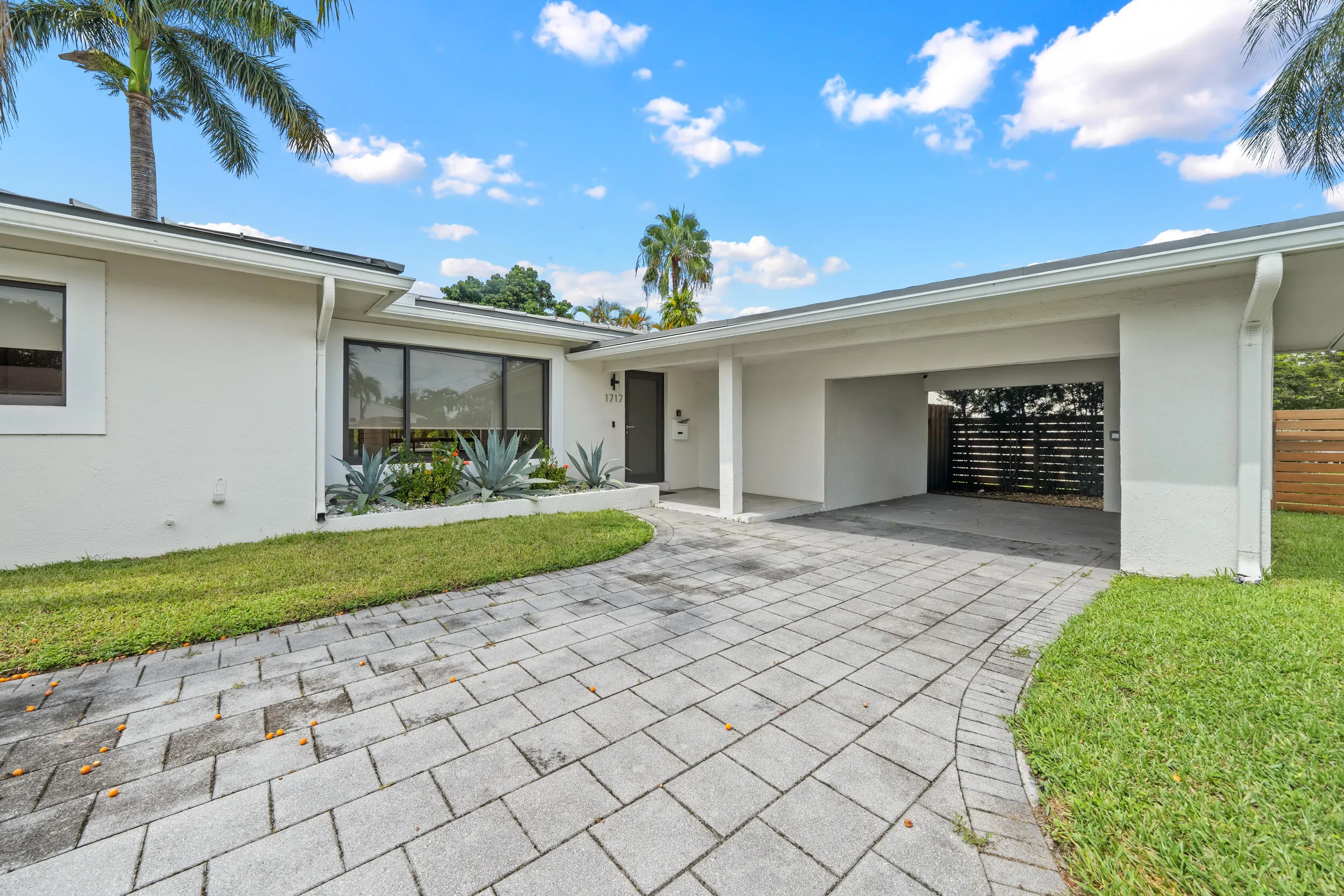 White stucco exterior with a flat roof, large picture windows, and a covered carport