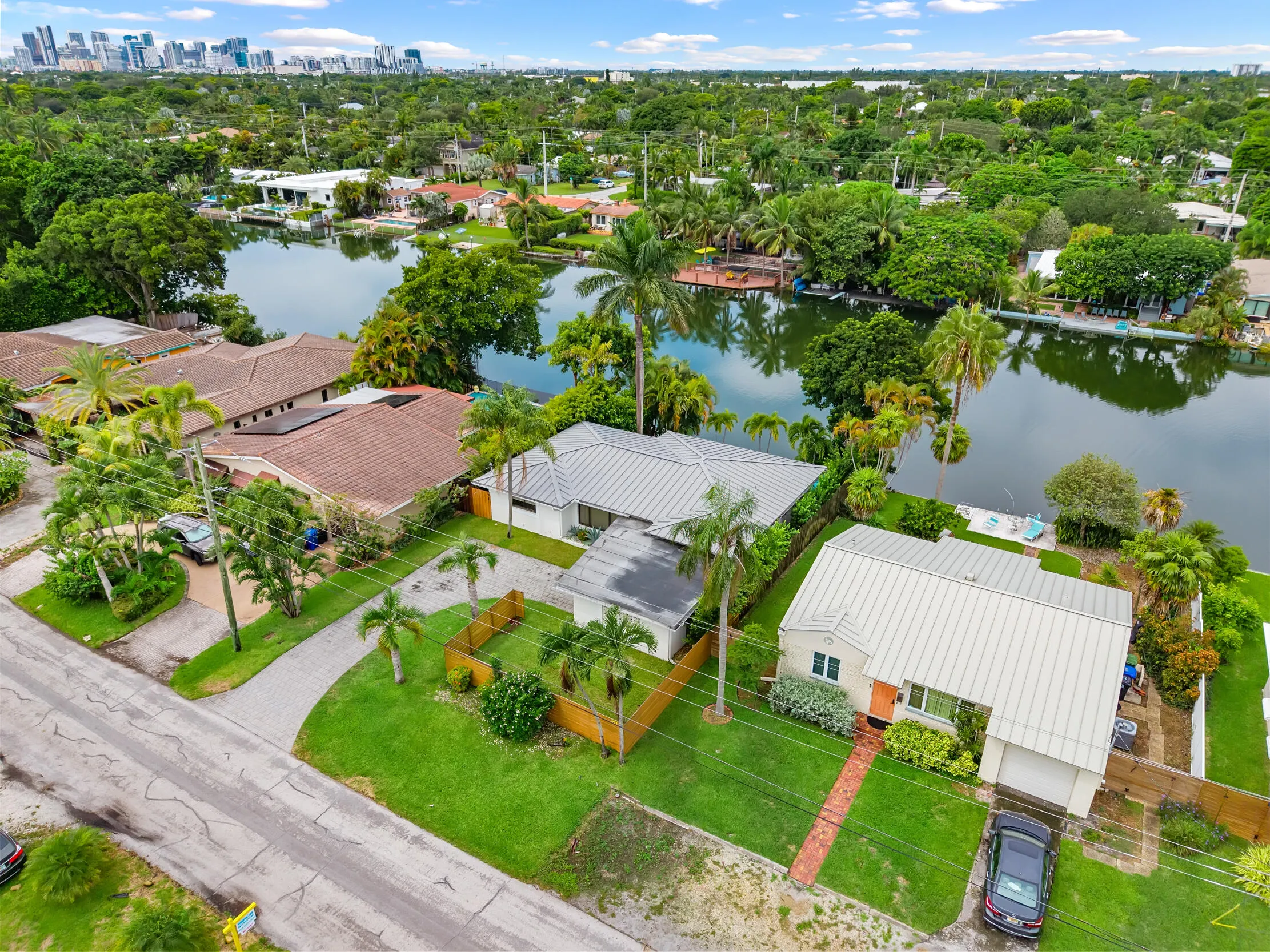 Waterfront property with a private dock, lush landscaping, and a metal roof