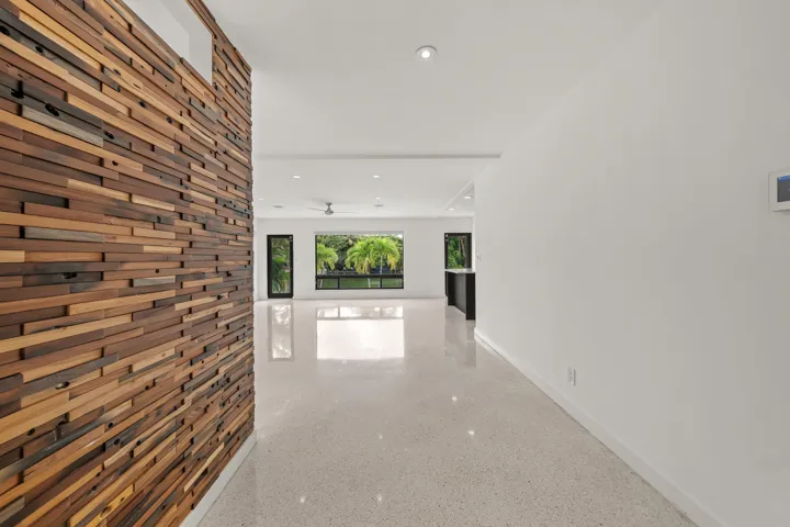 Wood-paneled accent wall, recessed lighting, polished flooring, contemporary ceiling fan, and black framed windows