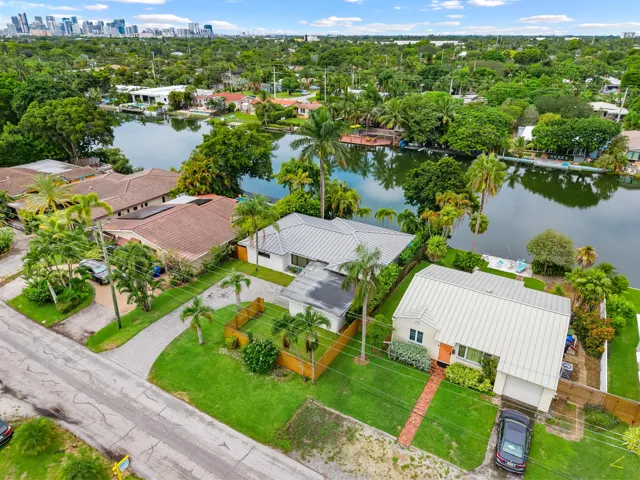 Waterfront property with a private dock, lush landscaping, and a metal roof