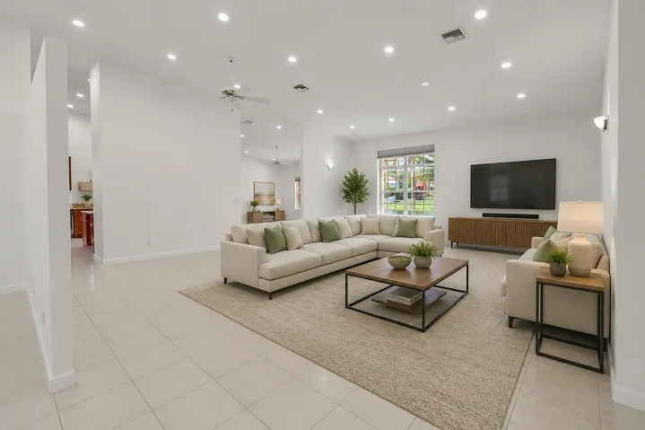 Spacious living area featuring neutral tile flooring, recessed lighting, and a ceiling fan