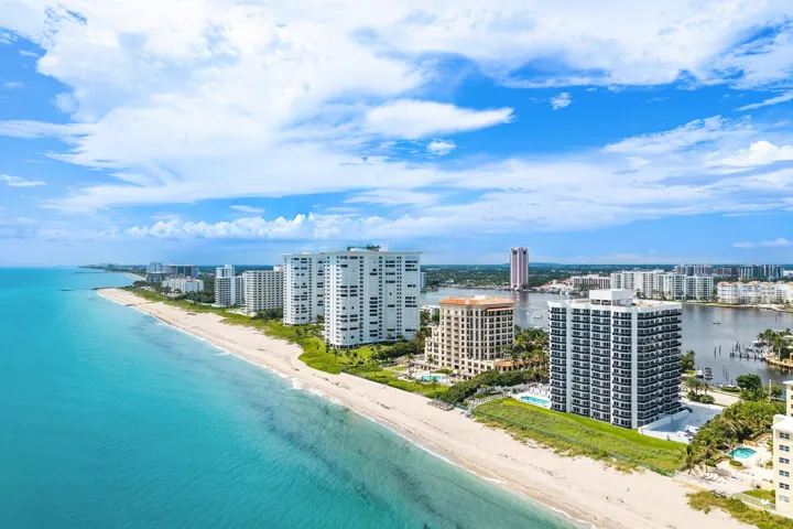 Expansive coastline featuring a sandy beach, multiple high-rise buildings, and a wide waterway with docked boats