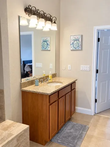 Bathroom vanity with wood cabinetry and ample lighting.