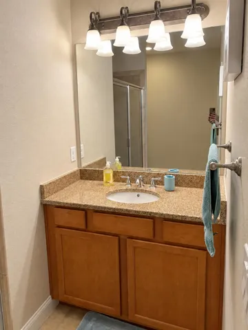 Bathroom vanity with wood cabinetry and large mirror.