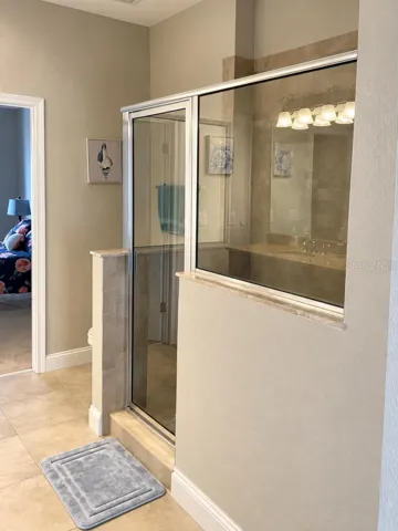 Glass-enclosed shower with tiled surround.