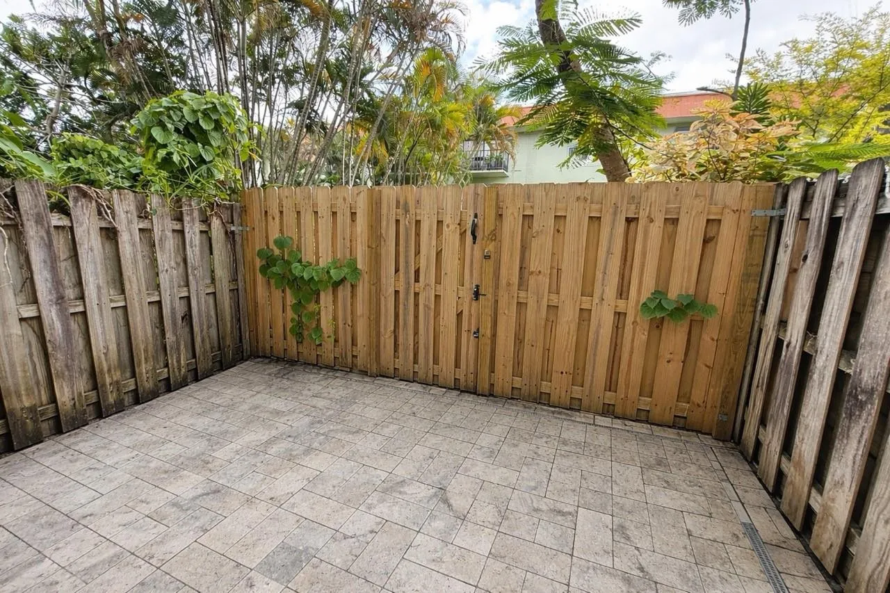 Paved outdoor patio with a plank wood fence and privacy gate