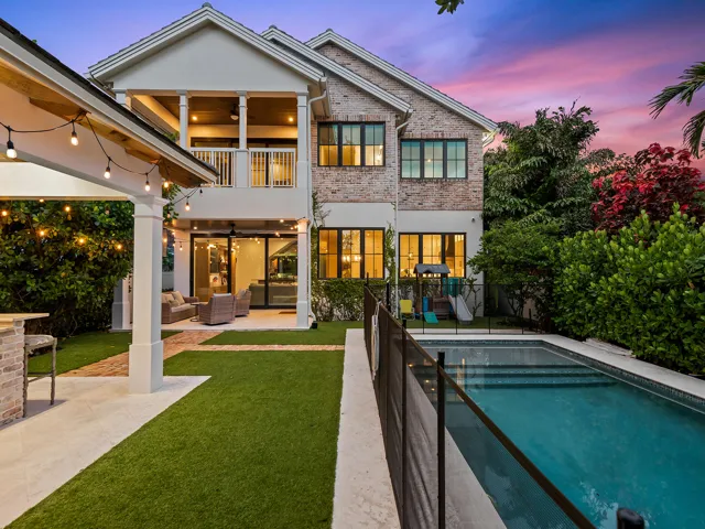 Backyard at dusk with pool, covered patio and string lights