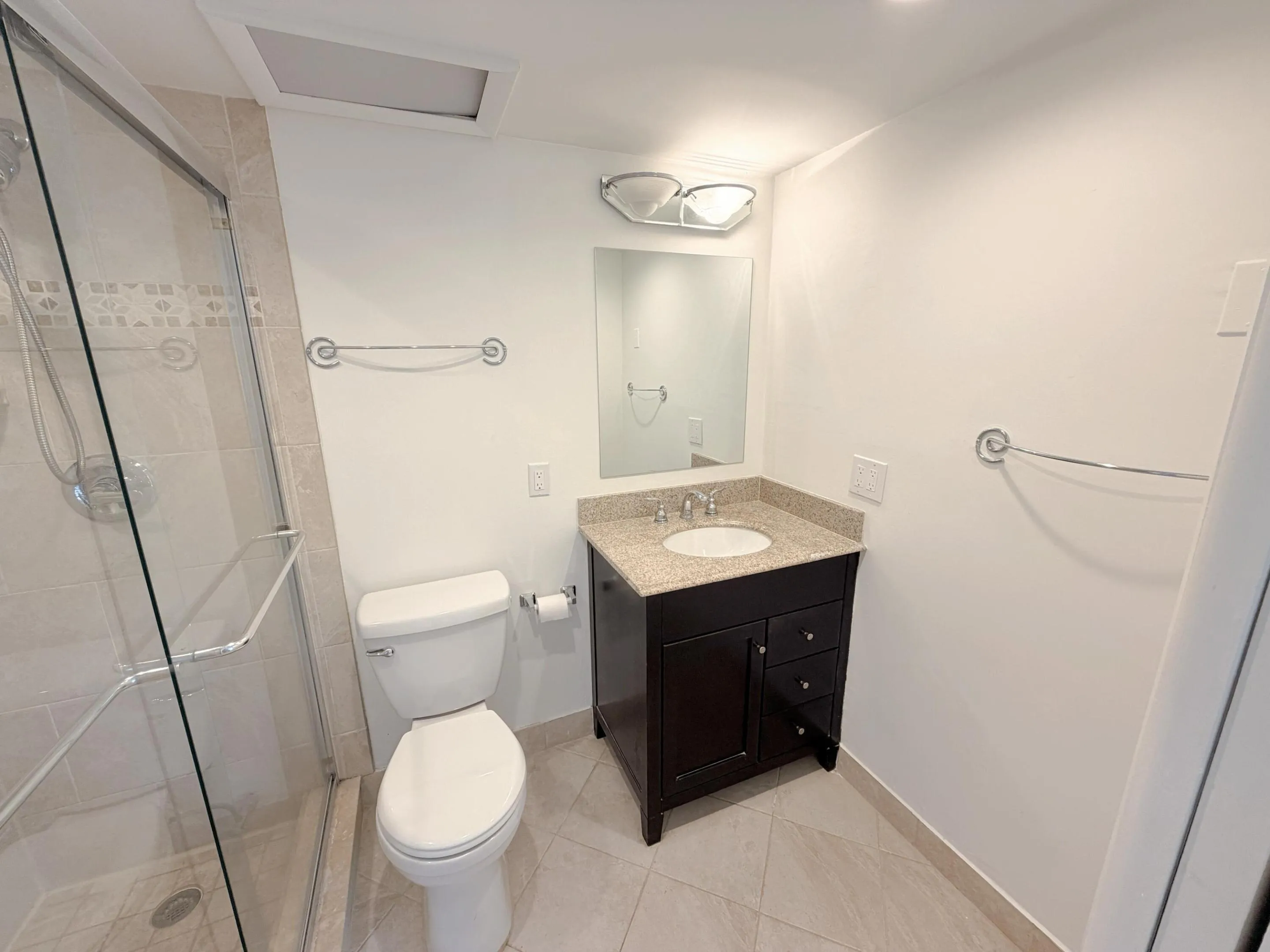 Modern bathroom featuring a dark wood vanity with dual-drawer storage, light stone countertop, and chrome faucet fixtures