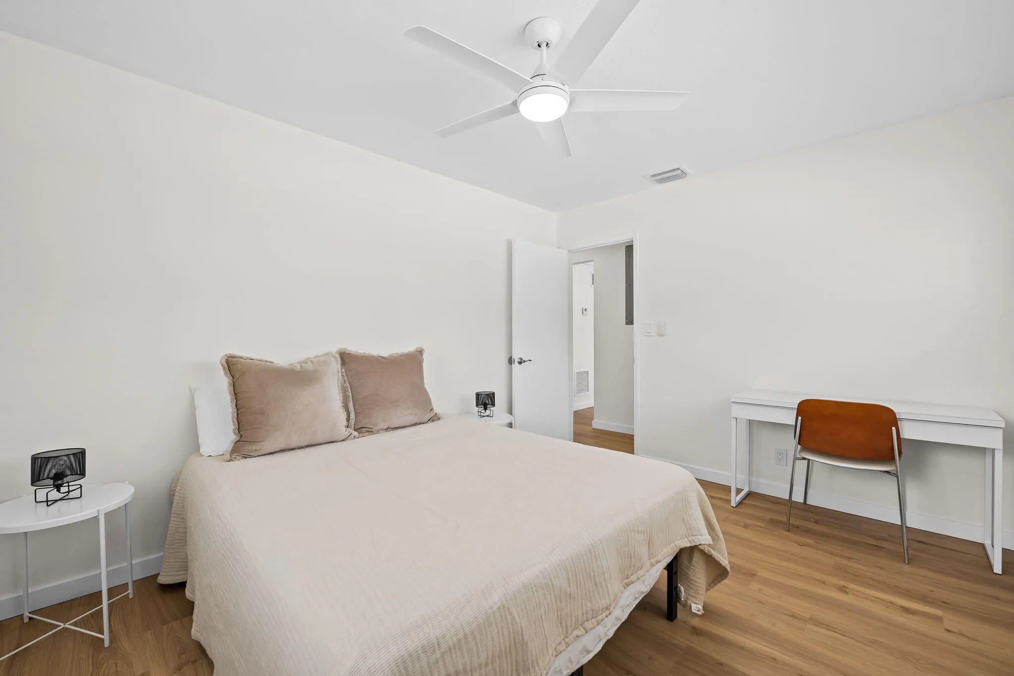 Wood-finish flooring throughout, bright white walls, and a contemporary ceiling fan with integrated lighting