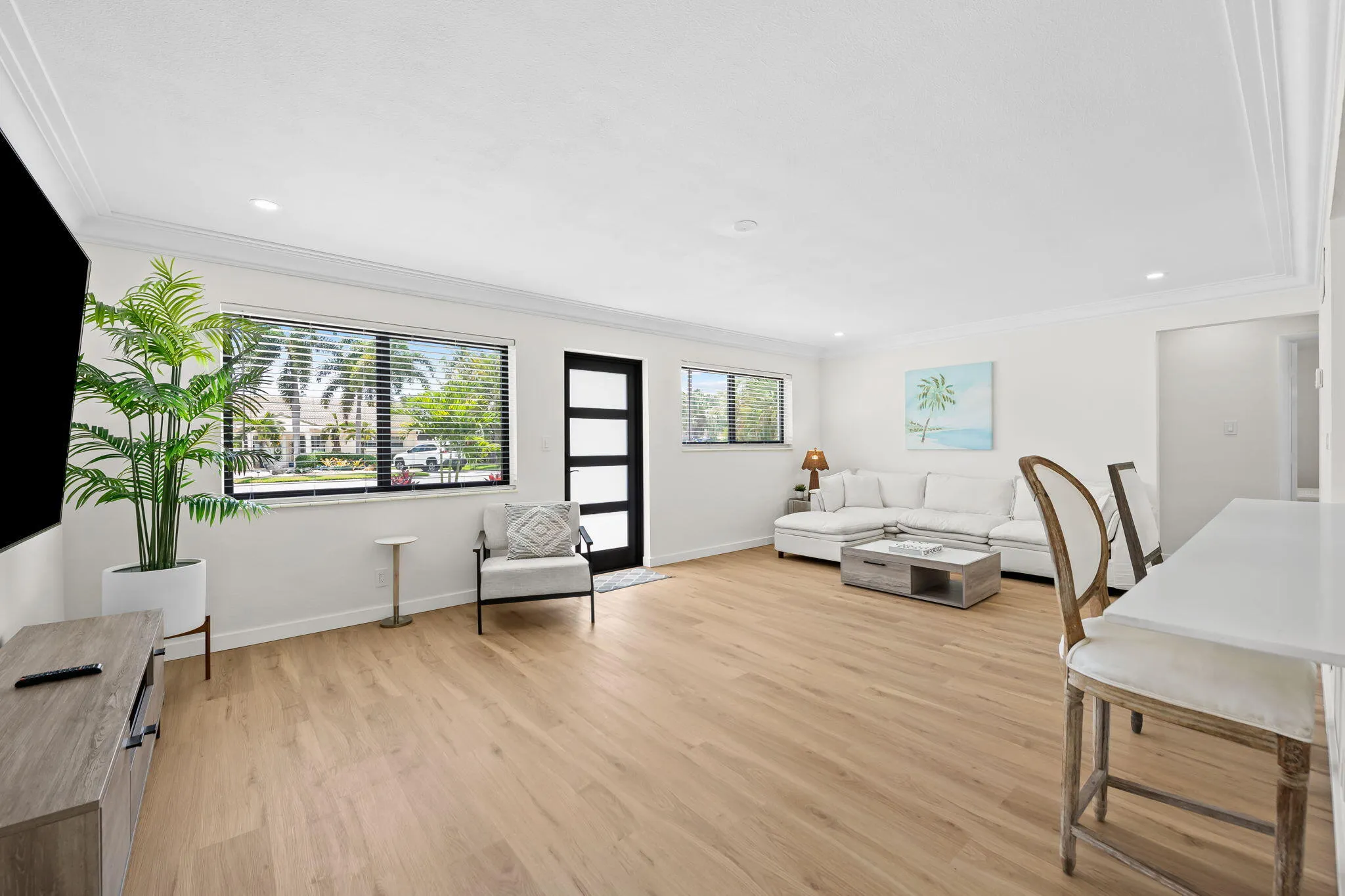 Recessed lighting, crown molding, wood-finish flooring, and a modern entry door with frosted glass panels