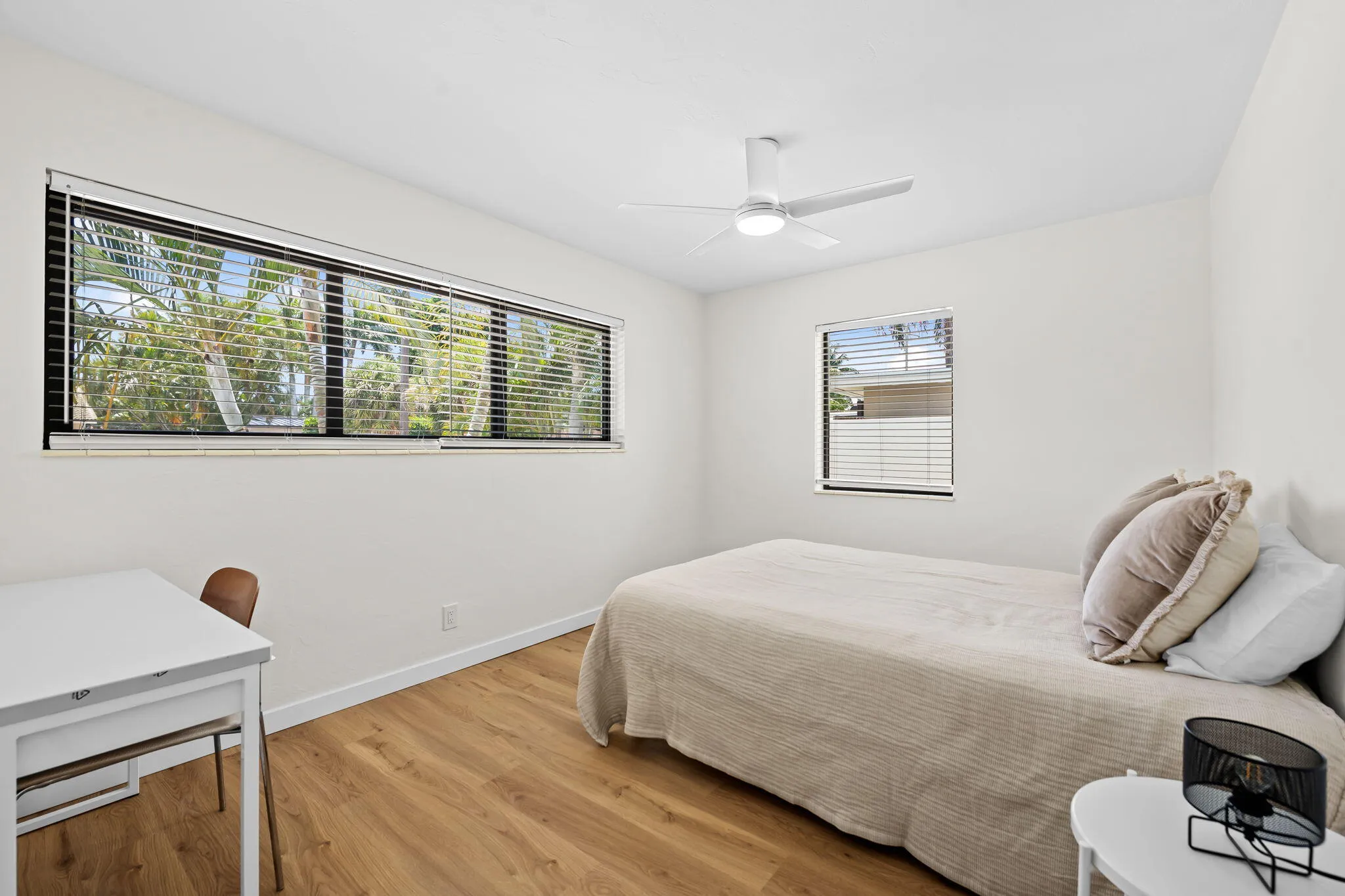 Wood-finish flooring, white walls, horizontal window, additional window, and a ceiling fan