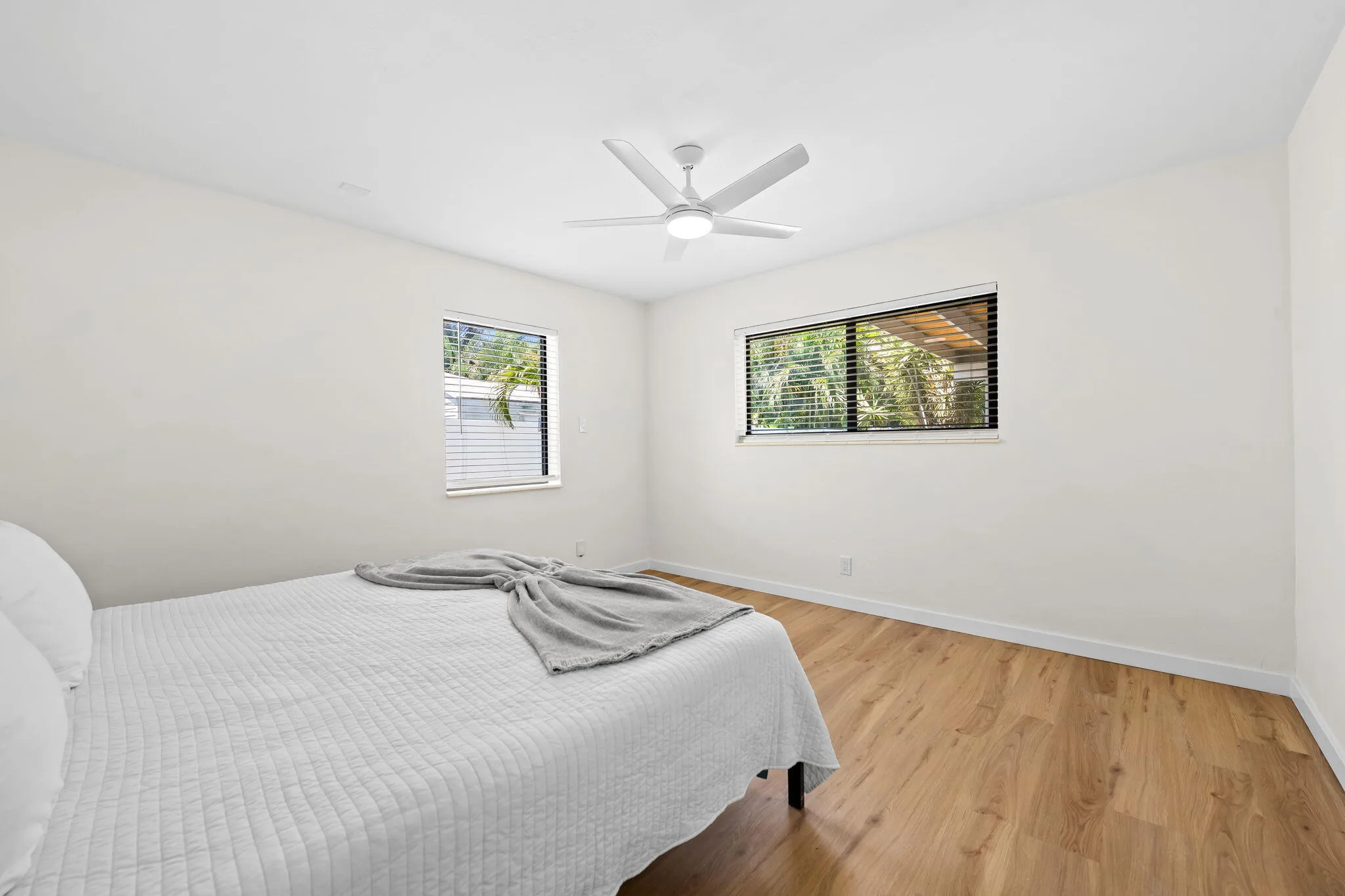 Recessed lighting, wood-finish flooring, white walls, and a ceiling fan with integrated lighting