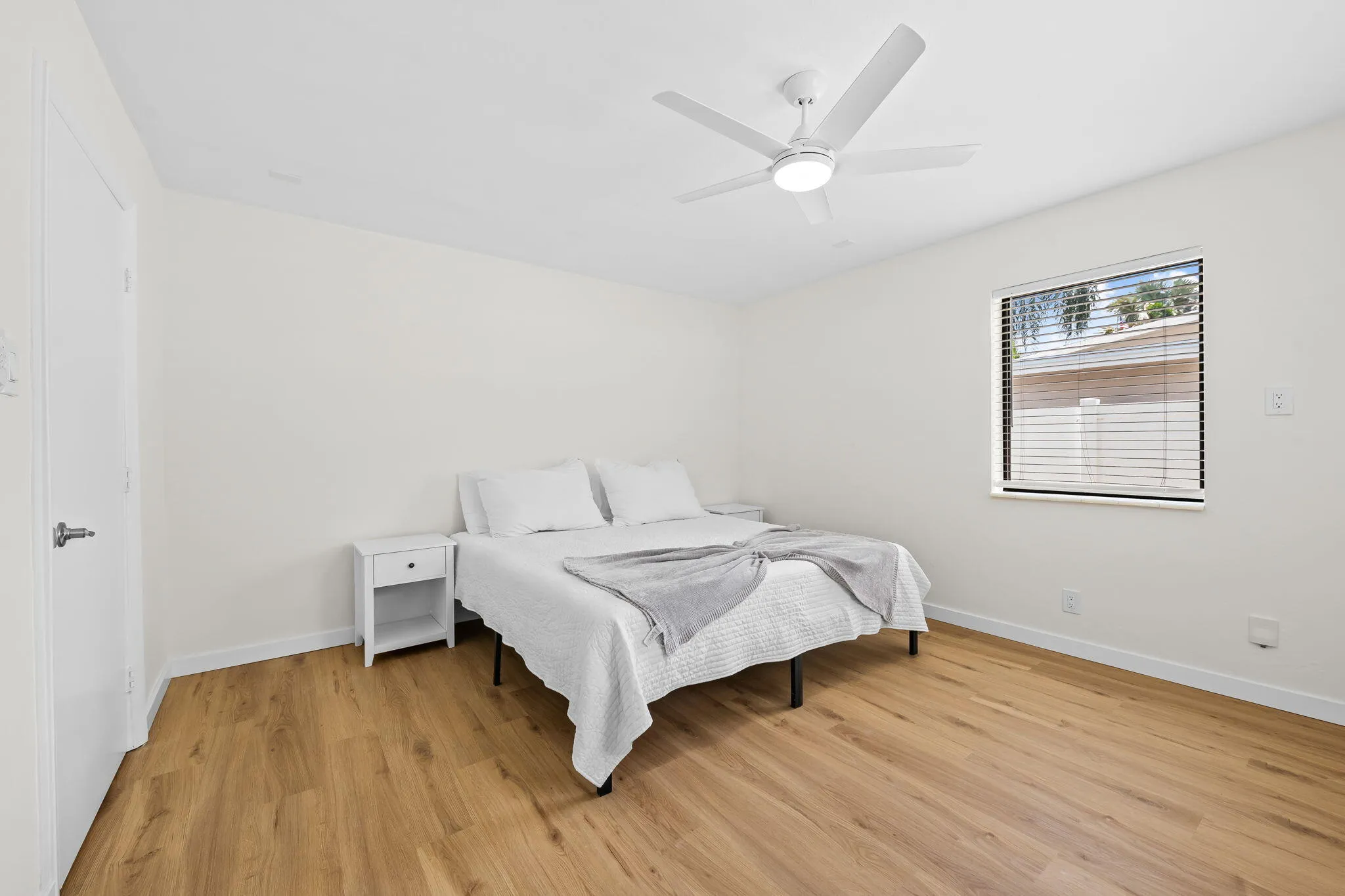 Wood-finish flooring, white walls, and a contemporary ceiling fan with integrated lighting