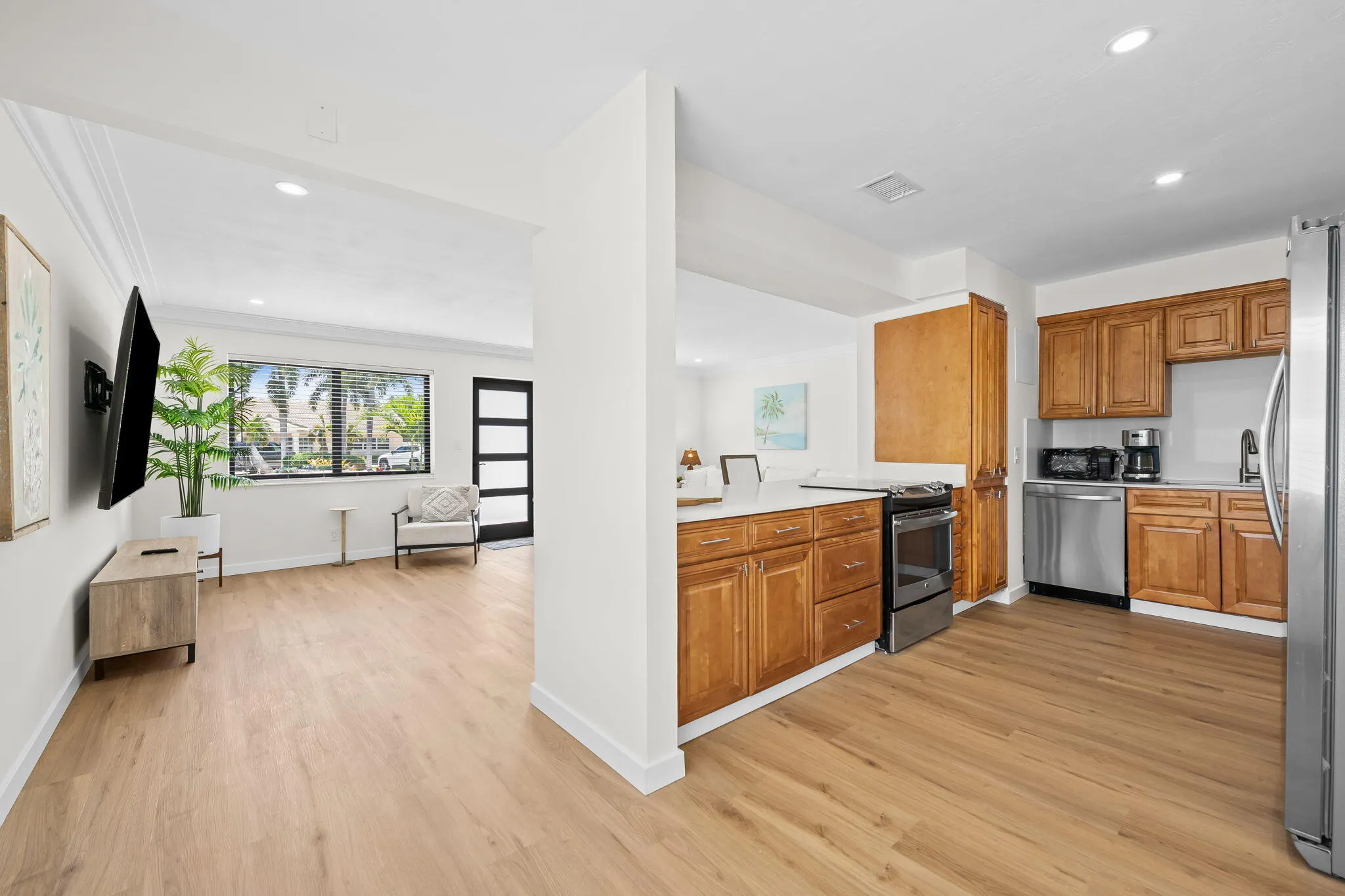 Kitchen with wood-finish flooring, stainless steel appliances, wood cabinetry, and white countertops