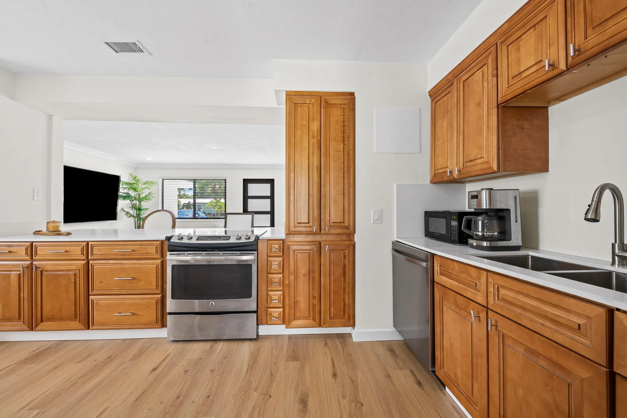 Wood-finish flooring, wood cabinetry, stainless steel range, double basin stainless steel sink, and light-toned countertops