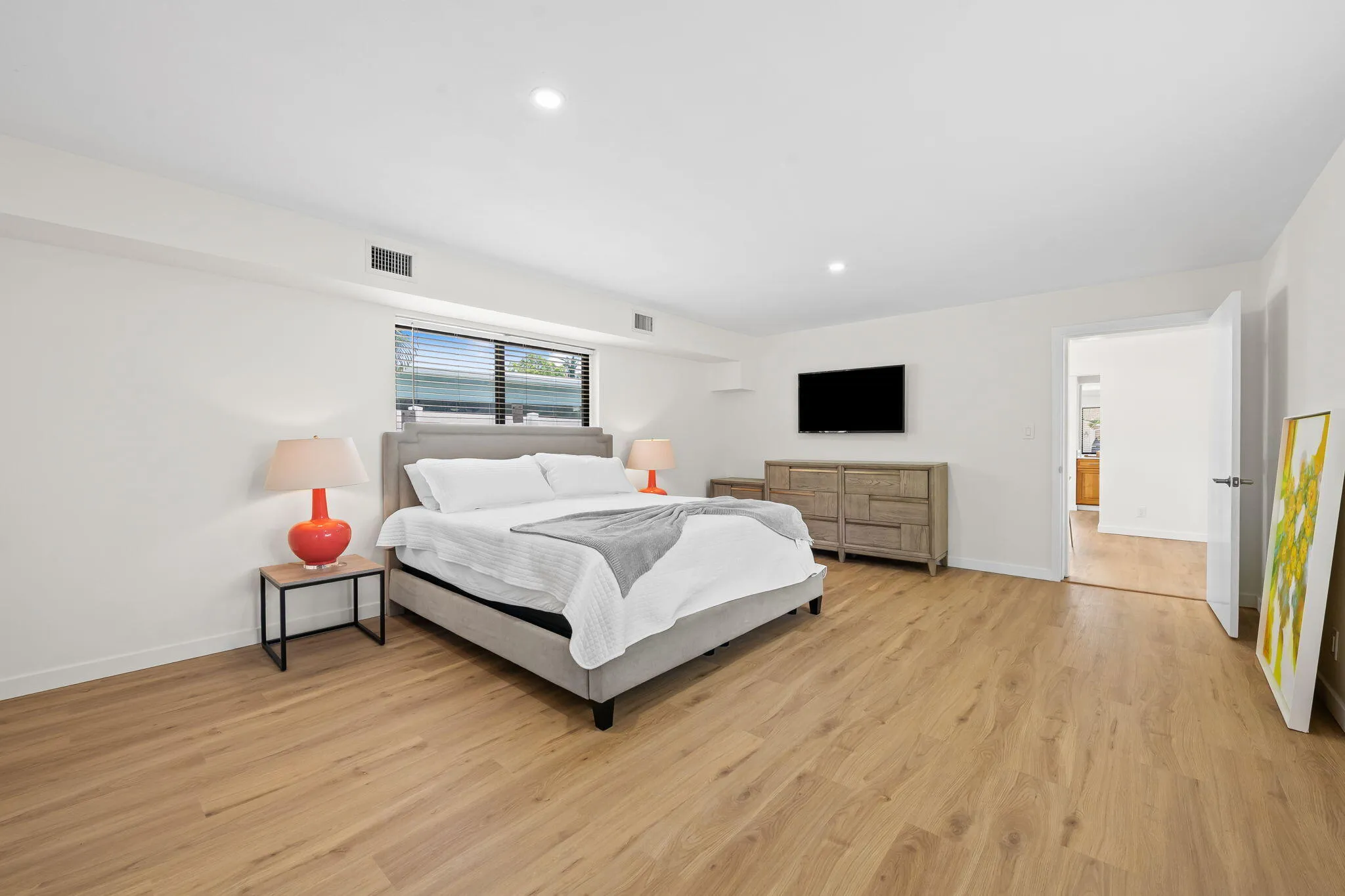 Spacious primary bedroom with hardwood flooring, recessed ceiling lighting, and large windows offering natural light