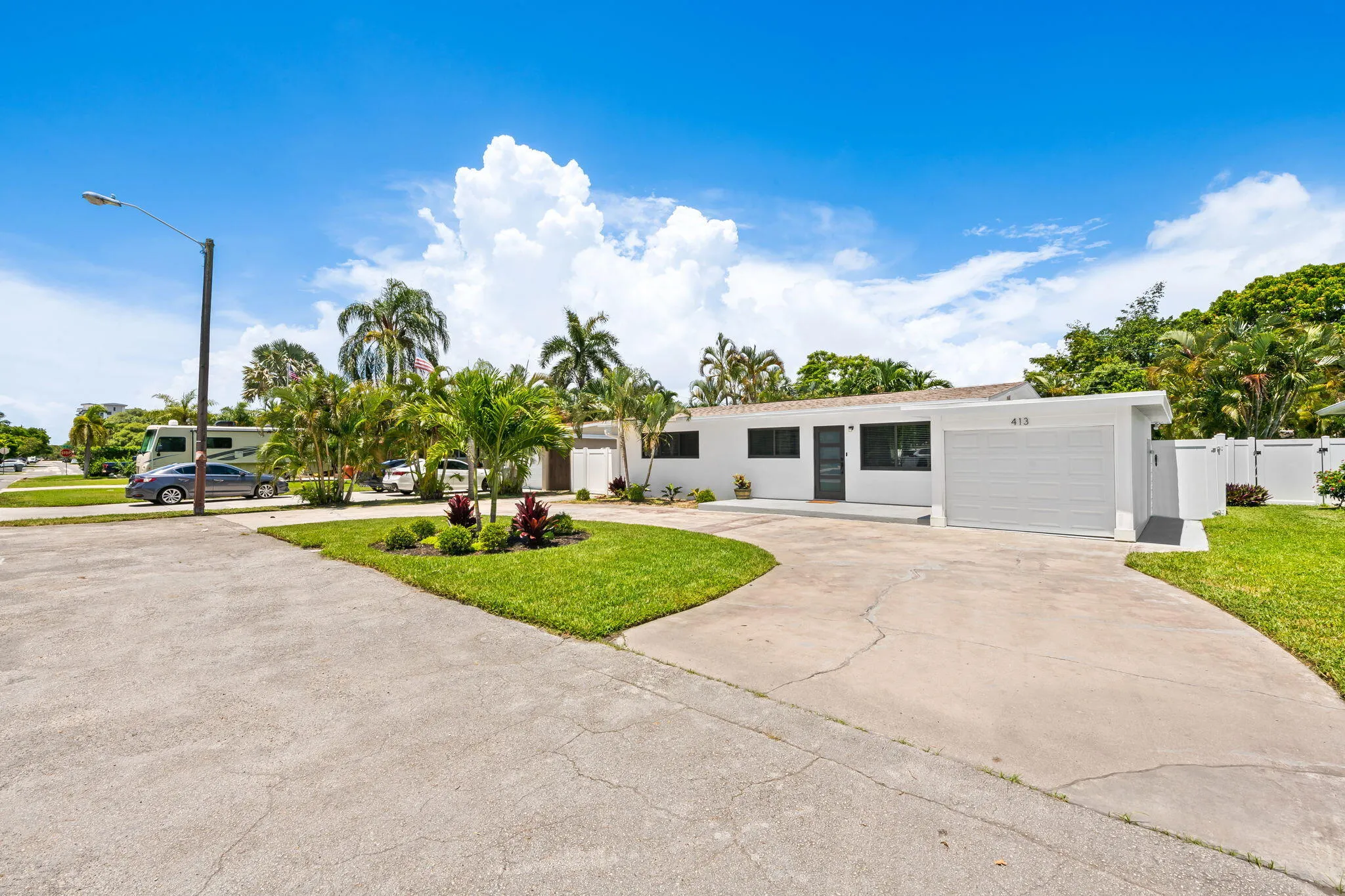 White-painted exterior with dark window frames, an attached garage with a white door, and a concrete driveway