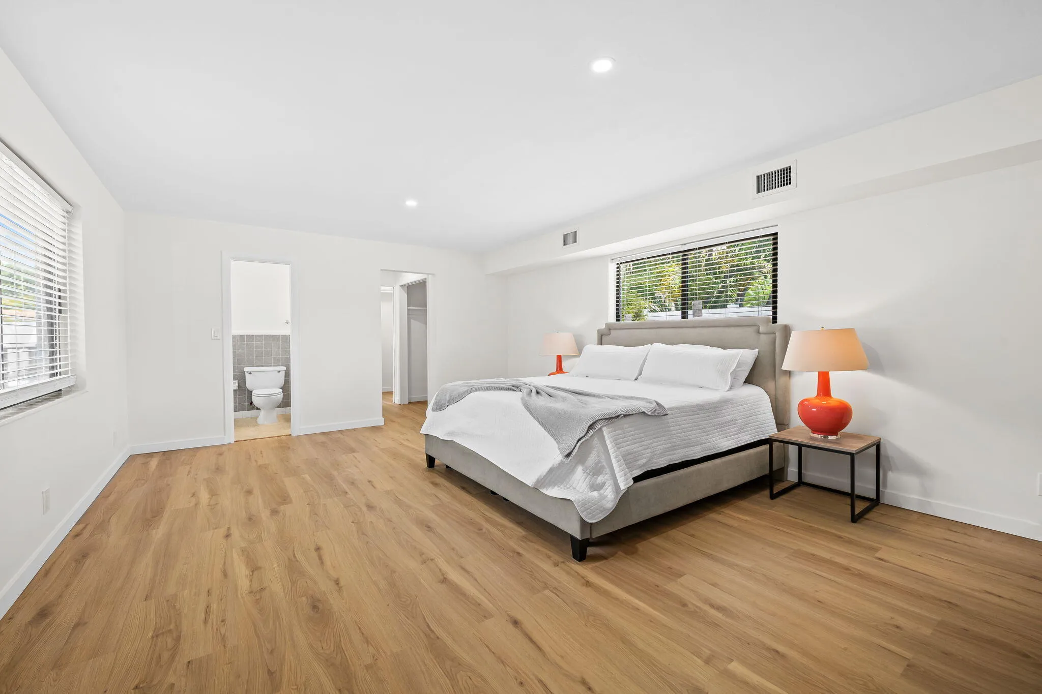 Spacious room featuring wood-finish flooring, recessed lighting, and multiple windows with blinds