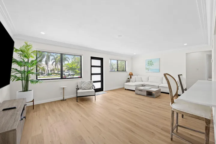 Recessed lighting, crown molding, wood-finish flooring, and a modern entry door with frosted glass panels