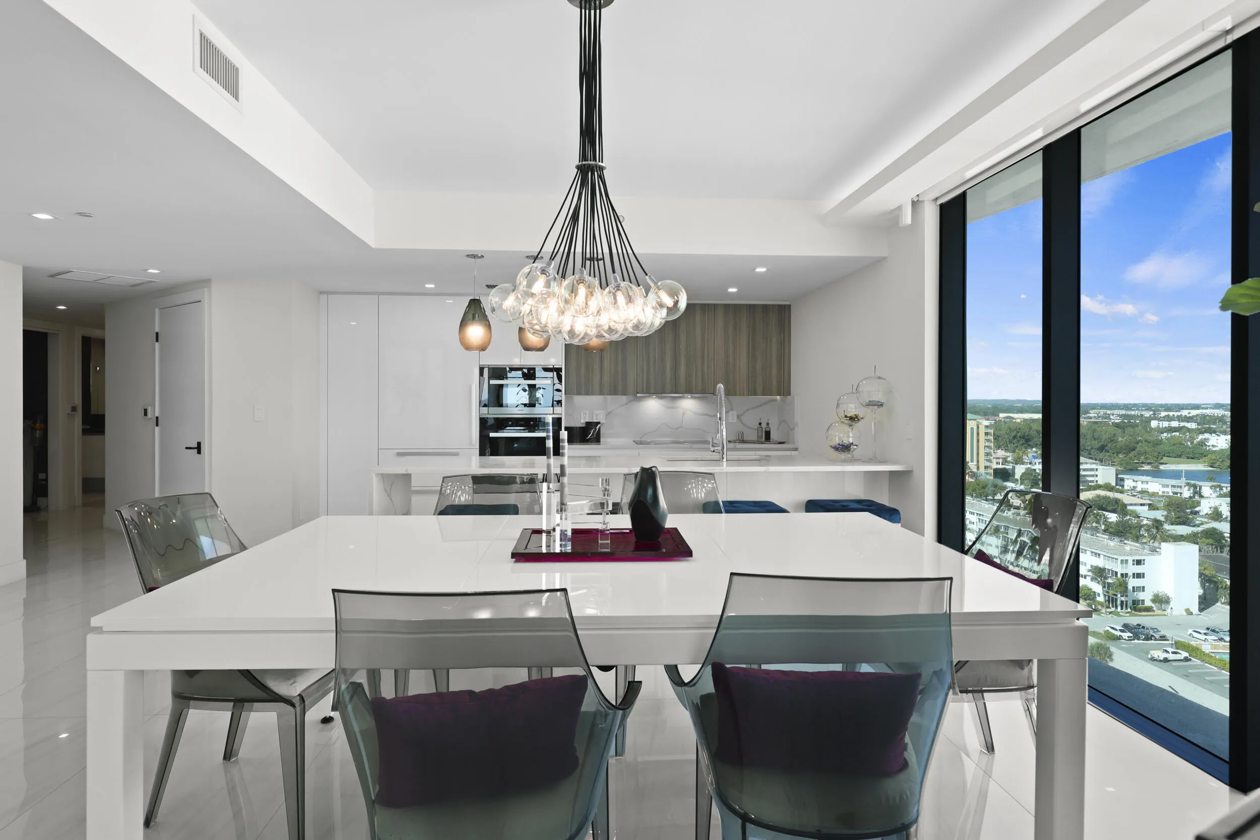 The dining area is illuminated by a designer chandelier and custom accent lighting, all framed by captivating views of the Atlantic Ocean and Intracoastal Waterway.