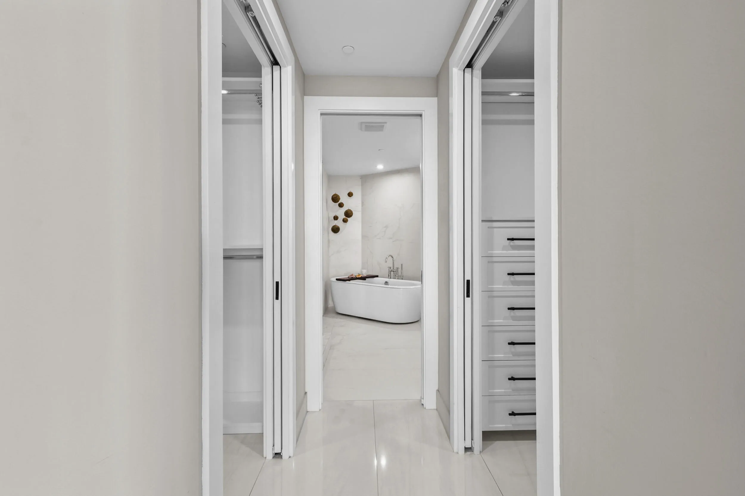 Step from your bedroom past fully customized his-and-hers closets and into a serene ensuite bathroom that feels like your own private spa, complete with custom porcelain tile, a frameless glass shower, freestanding soaking tub and floating vanity with leathered quartzite countertops, all illuminated by designer sconces.
