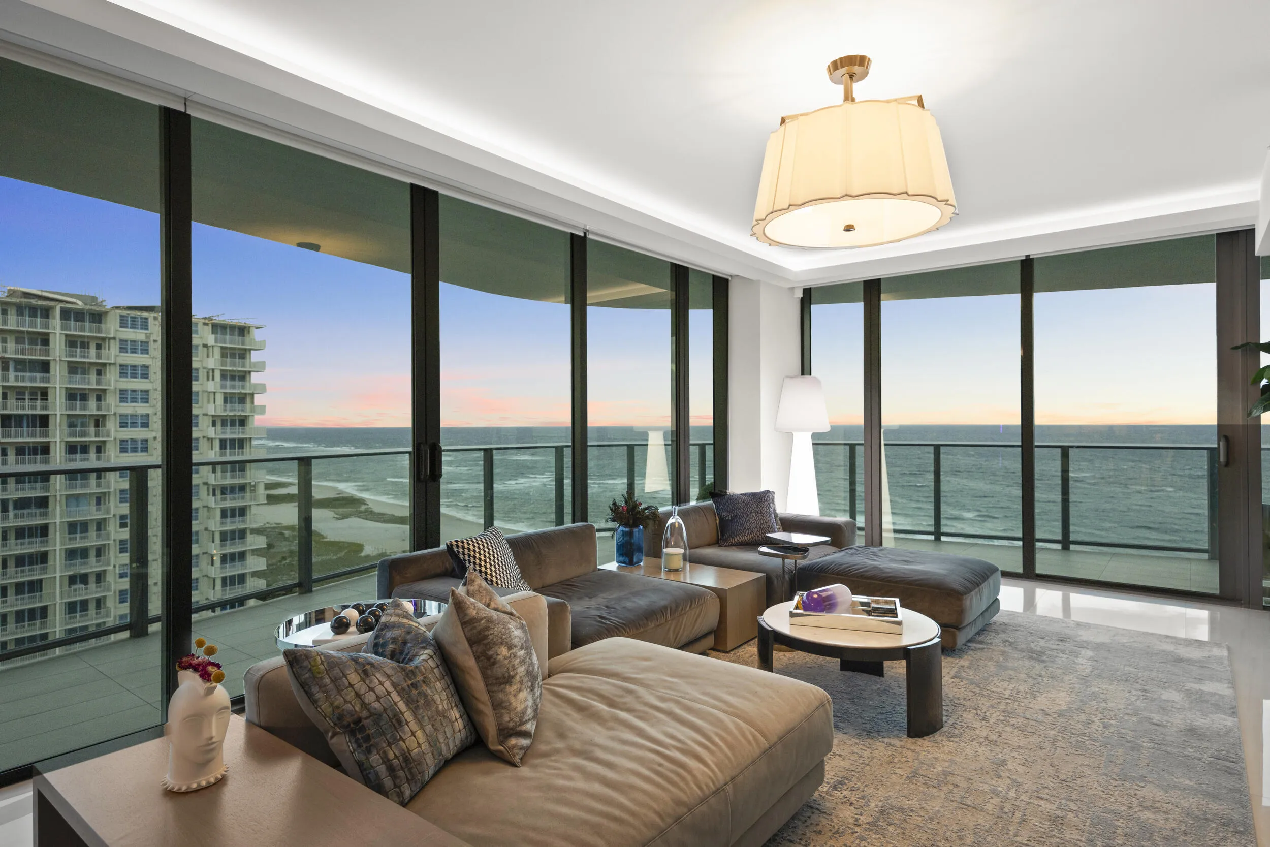 As the sun sets, custom lighting and illuminated accent walls glow in harmony with the soft, colorful evening light that fills the residence.