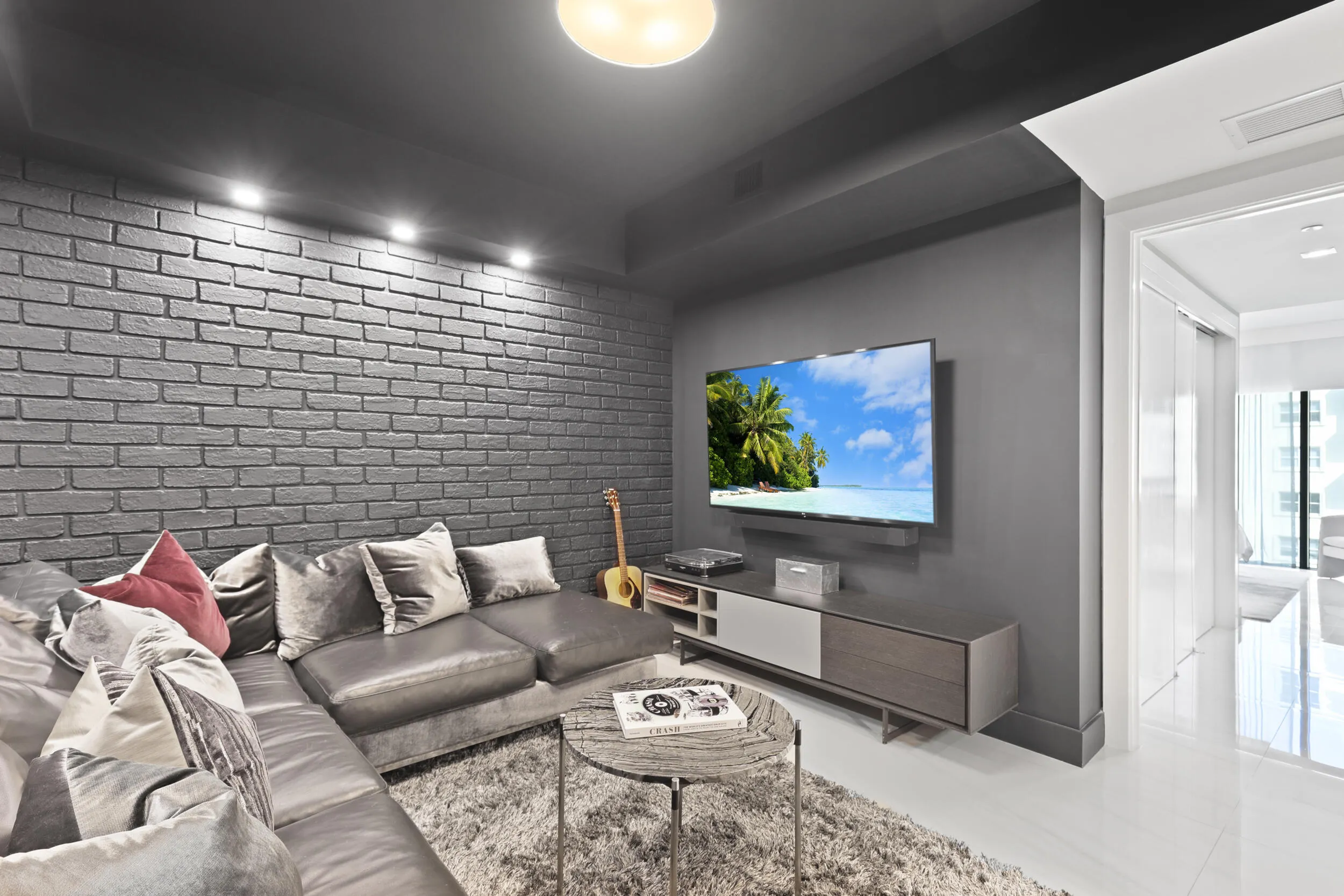 A true showstopper, the den brings bold character and unexpected warmth to this oceanfront residence. A custom faux brick accent wall and dramatic lighting create an unforgettable setting for a movie theater, game room, private office or intimate lounge. Rarely found in a contemporary oceanfront home, this versatile space may also be adapted into a fourth bedroom if desired.