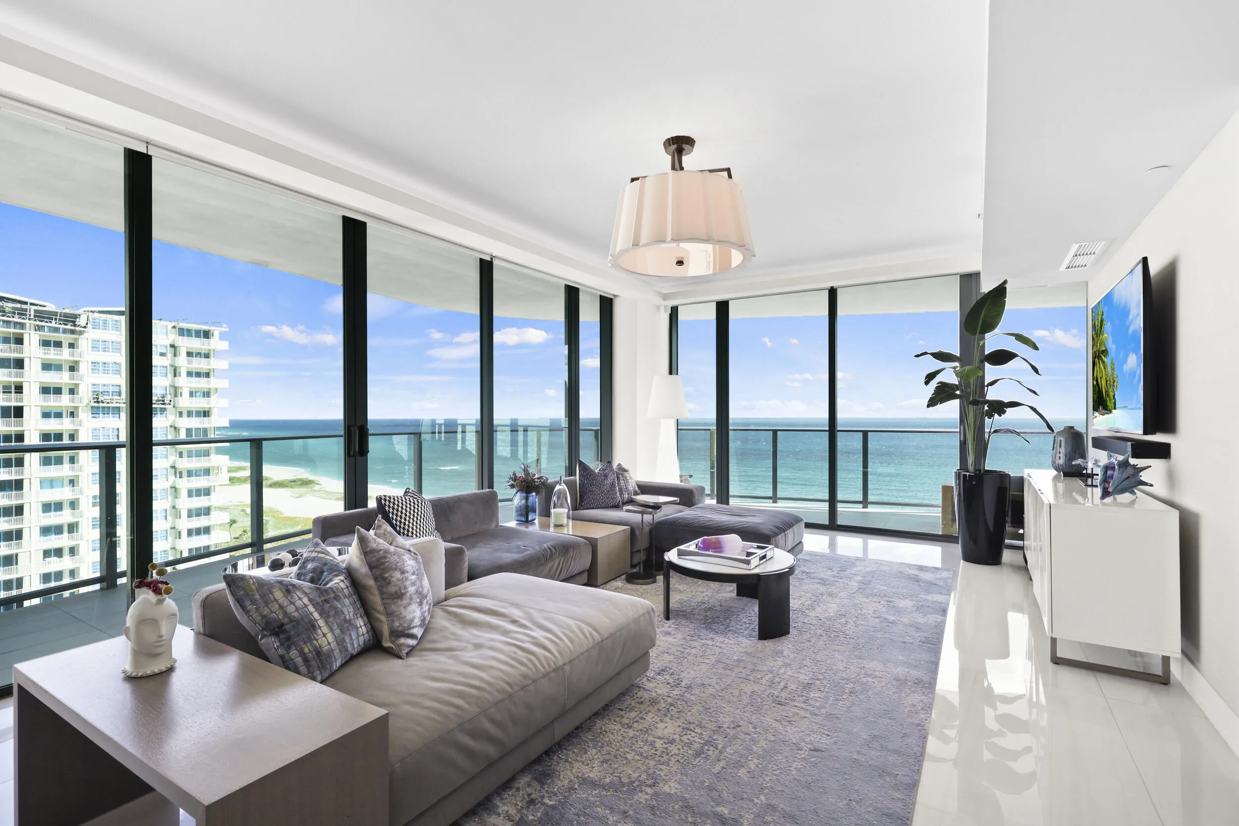 Framed by floor-to-ceiling impact glass, the living room opens seamlessly onto the wraparound balcony, creating an inviting retreat to unwind while enjoying sweeping views and refreshing ocean breezes.