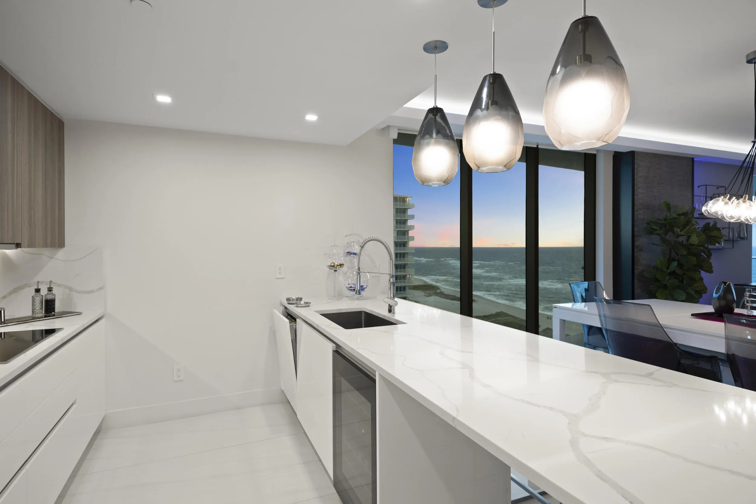 As the sun sets, custom lighting and illuminated accent walls glow in harmony with the soft, colorful evening light that fills the residence.