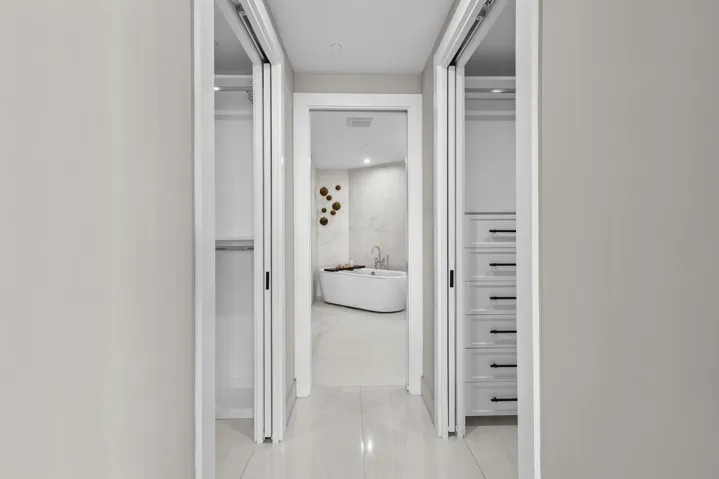 Step from your bedroom past fully customized his-and-hers closets and into a serene ensuite bathroom that feels like your own private spa, complete with custom porcelain tile, a frameless glass shower, freestanding soaking tub and floating vanity with leathered quartzite countertops, all illuminated by designer sconces.
