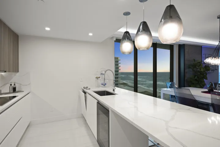 As the sun sets, custom lighting and illuminated accent walls glow in harmony with the soft, colorful evening light that fills the residence.