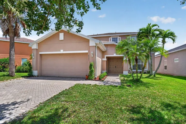 Two-story residence featuring a two-car garage, paver driveway, and a welcoming front entry