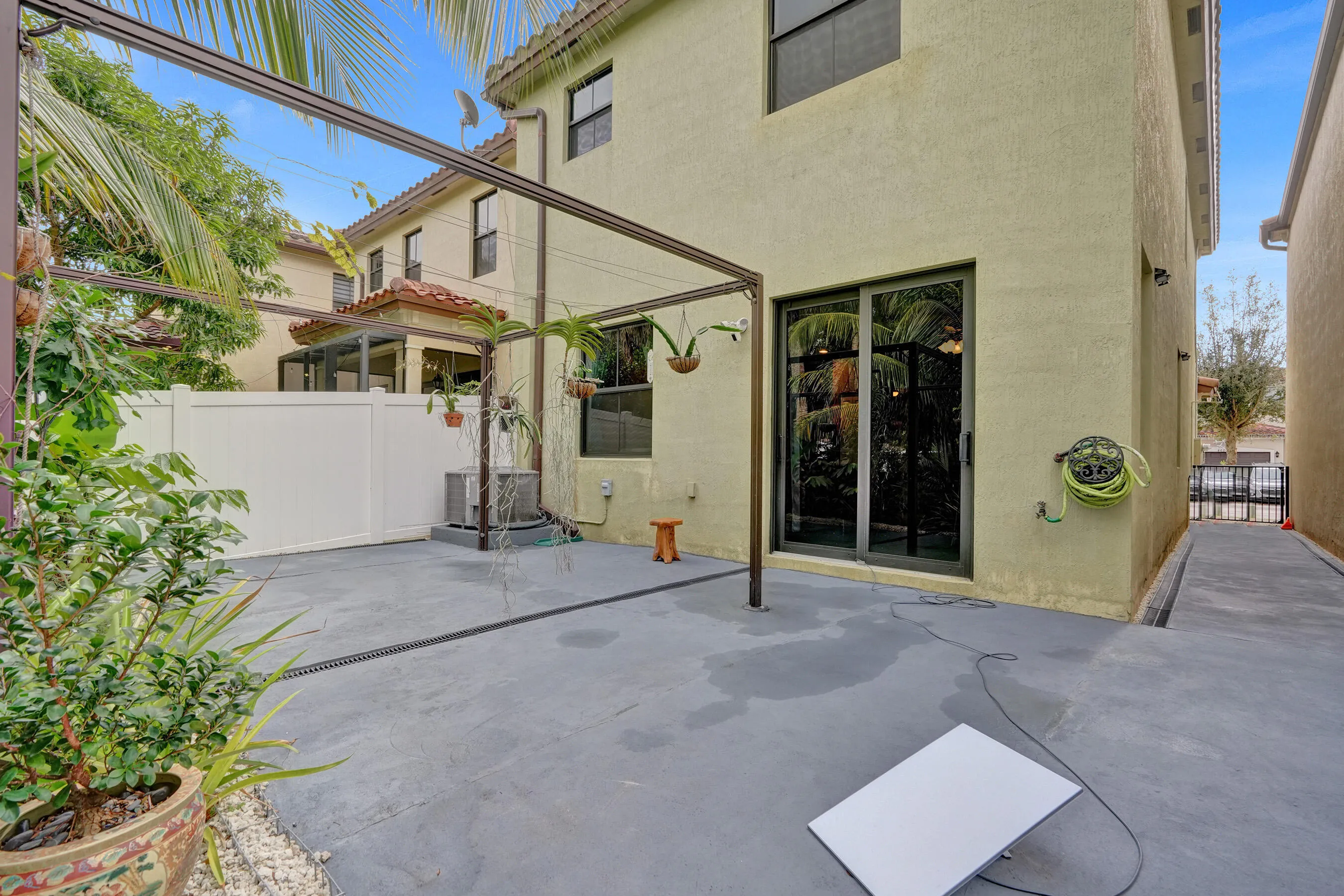 Patio area featuring a dark gray concrete surface, a white privacy fence, and a metal pergola structure