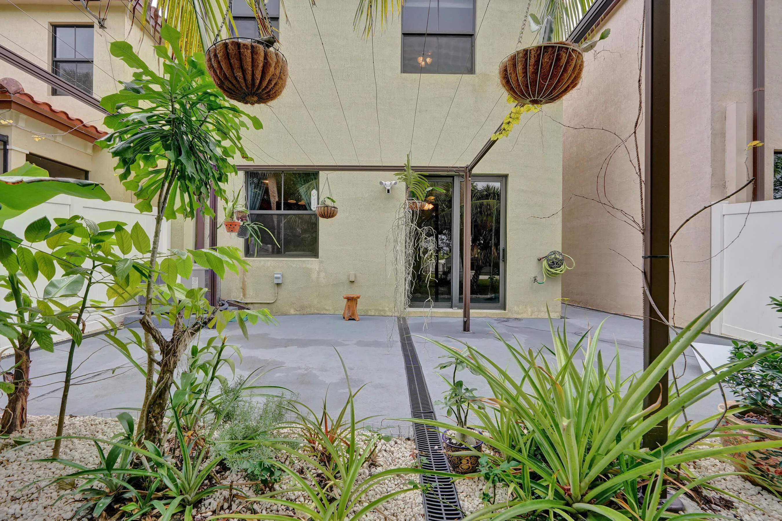 Patio featuring a drainage system, sliding glass doors, and established landscaping with various plantings
