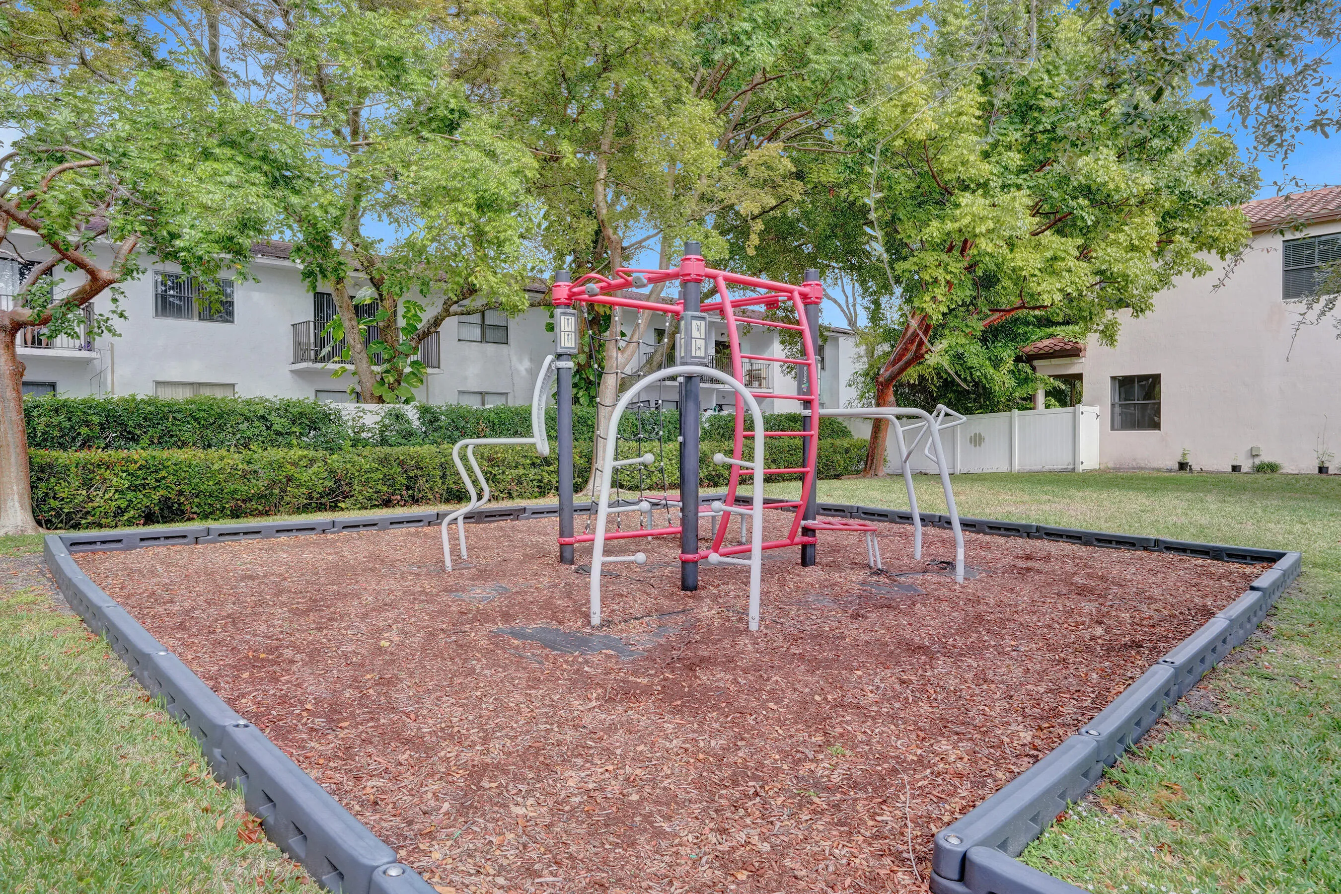 Recreational play structure with climbing elements, surrounded by wood chip surfacing and a perimeter border