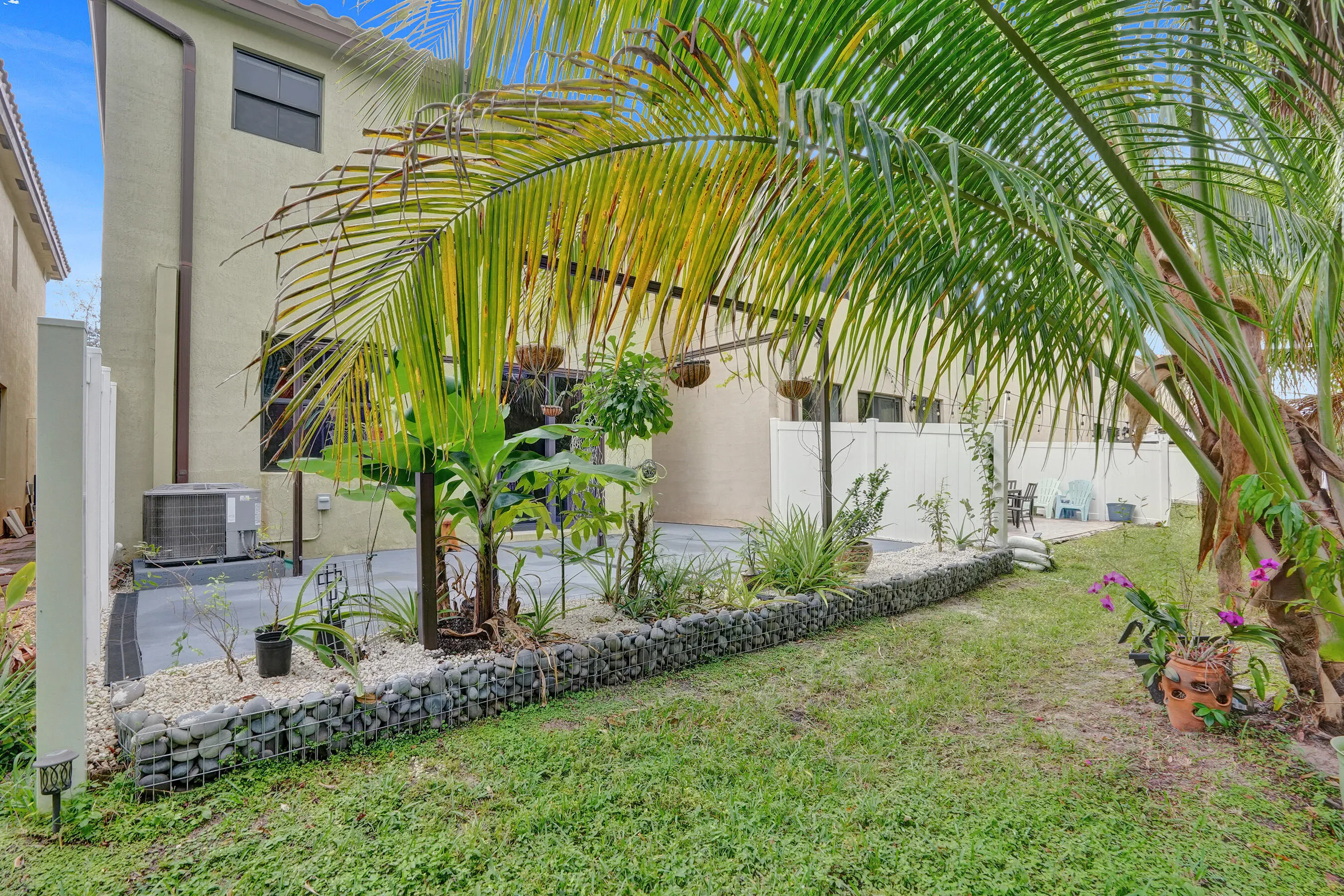 Private outdoor area featuring established palm trees and a gabion rock planter
