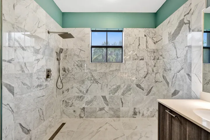 Walk-in shower with full-height marble-style tiling, rain shower head, and an inset window