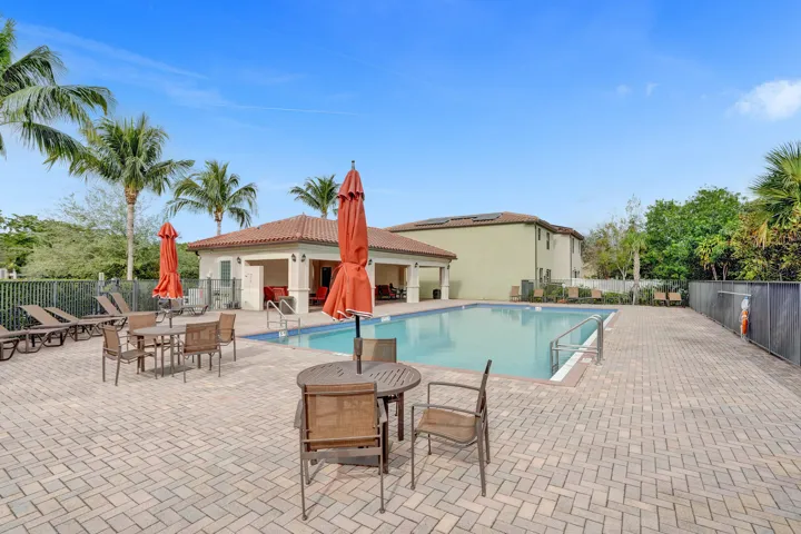 Resort-style pool area featuring a rectangular pool, paver deck, and covered poolside cabana