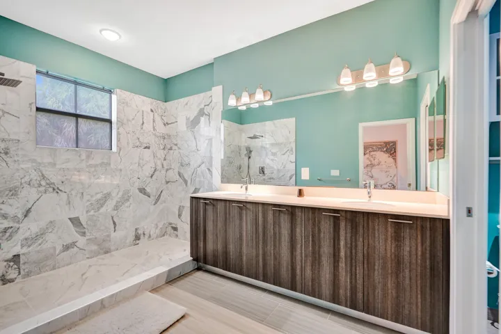 Dual vanity with undermount sinks, wood-finish cabinetry, and contemporary light fixtures