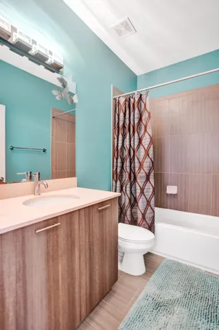 Vanity with wood-finish cabinetry, integrated sink, and contemporary faucet