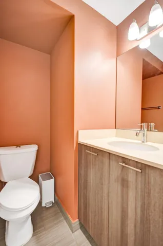 Wood-finish vanity with a light-toned countertop, integrated sink, and modern faucet