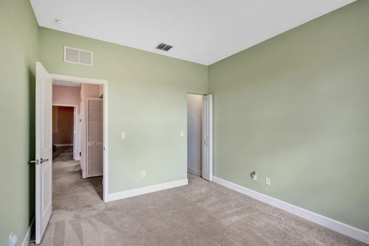 Plush carpet flooring, light green wall paint, white trim, recessed lighting, and a solid core door