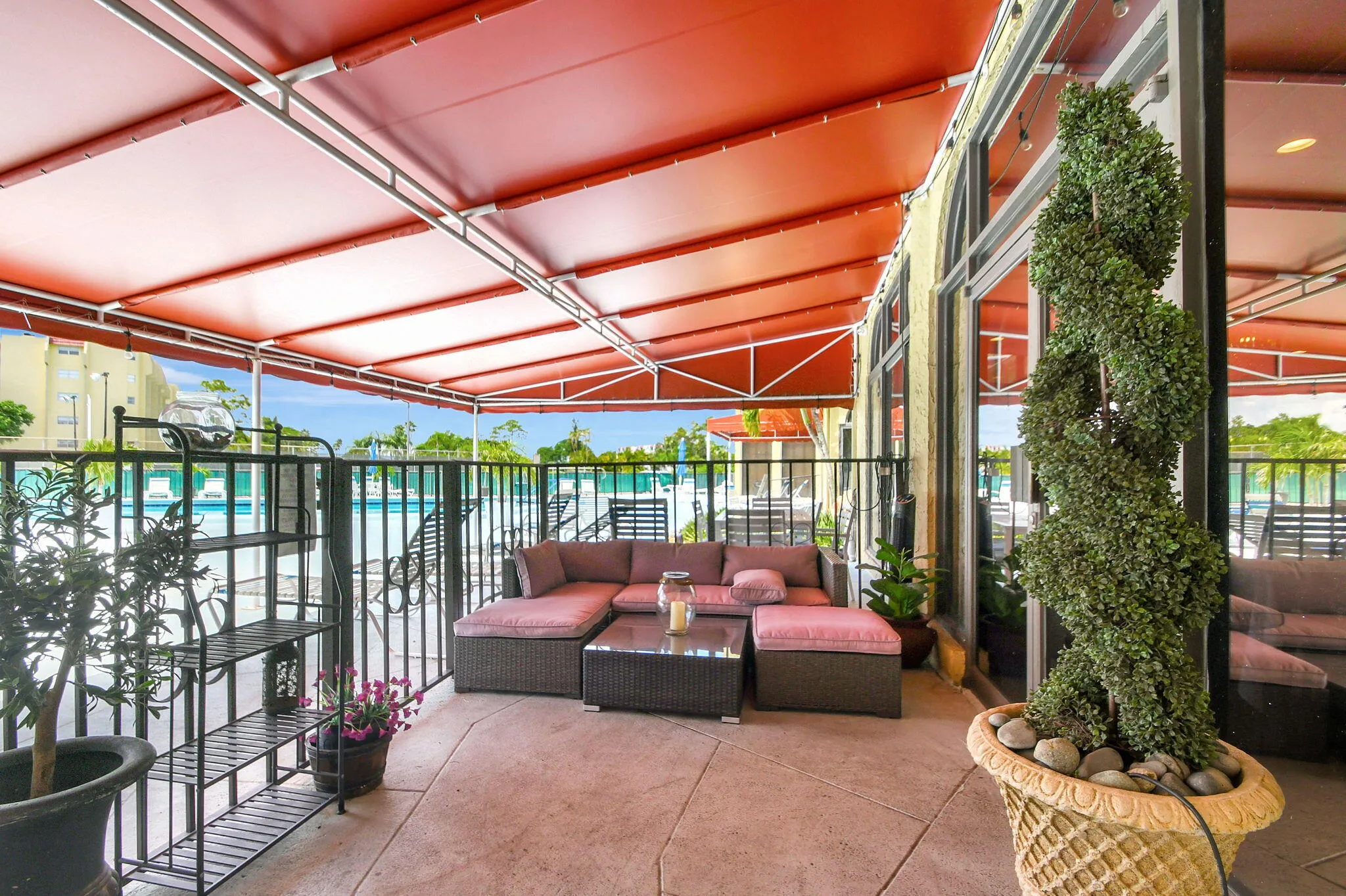 Covered patio with a red awning, concrete flooring, and full-height windows
