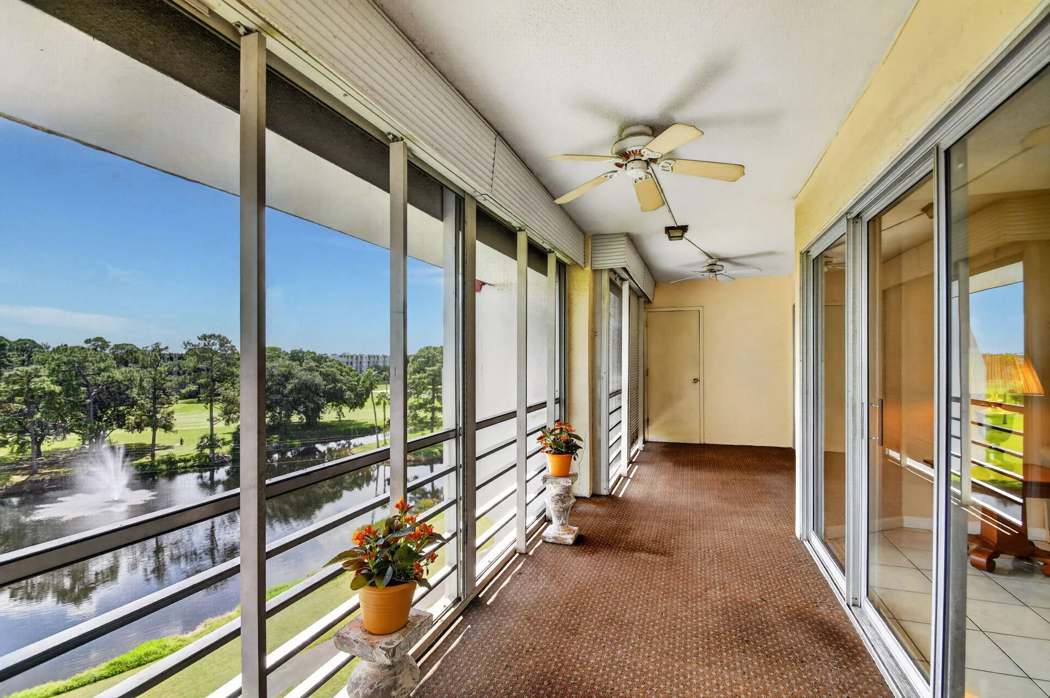 Enclosed balcony with large sliding glass panels, Concrete flooring, g two ceiling fans