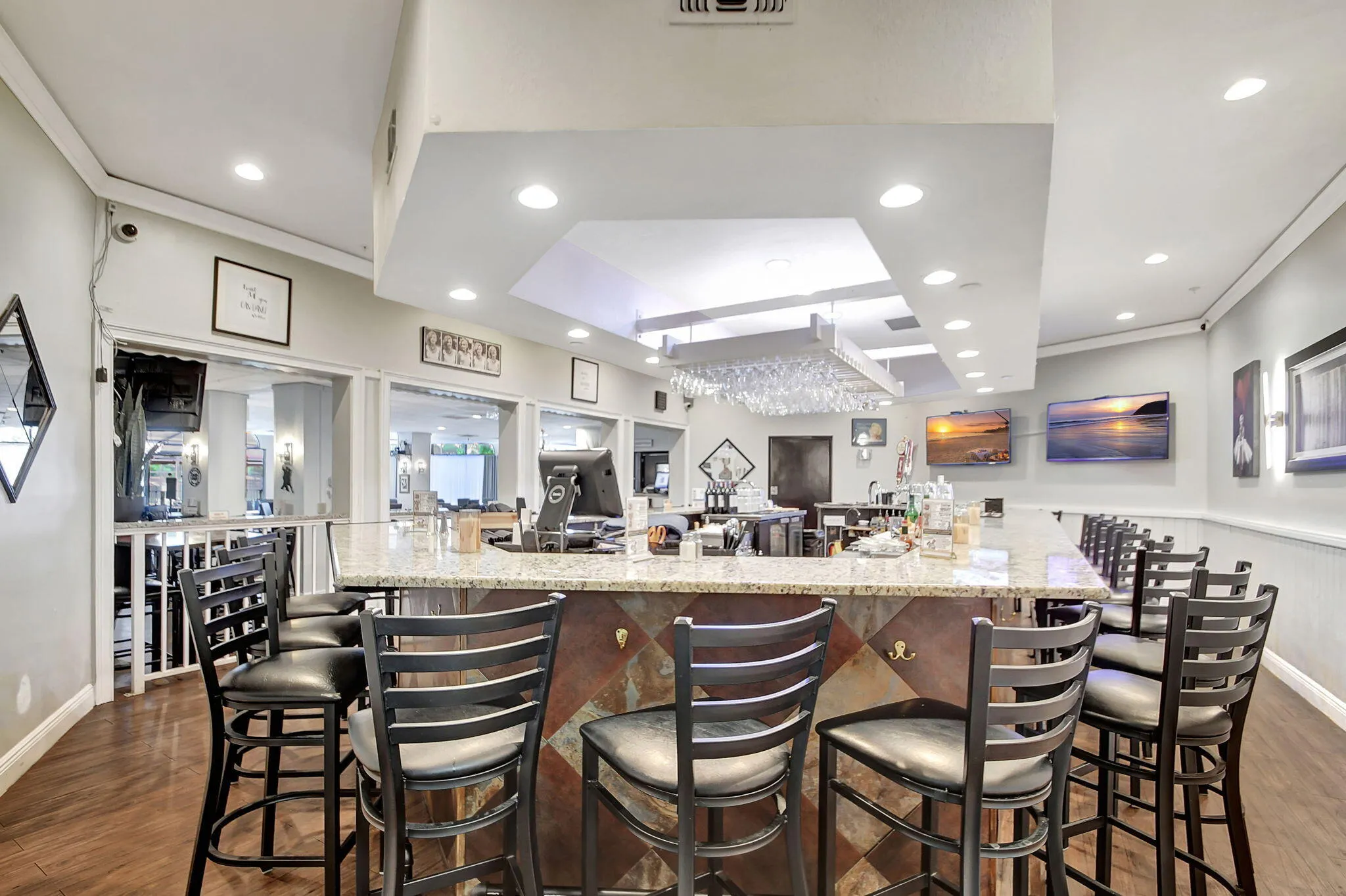 Granite-finish bar top with integrated seating, recessed lighting, wood-finish flooring, and a glass rack