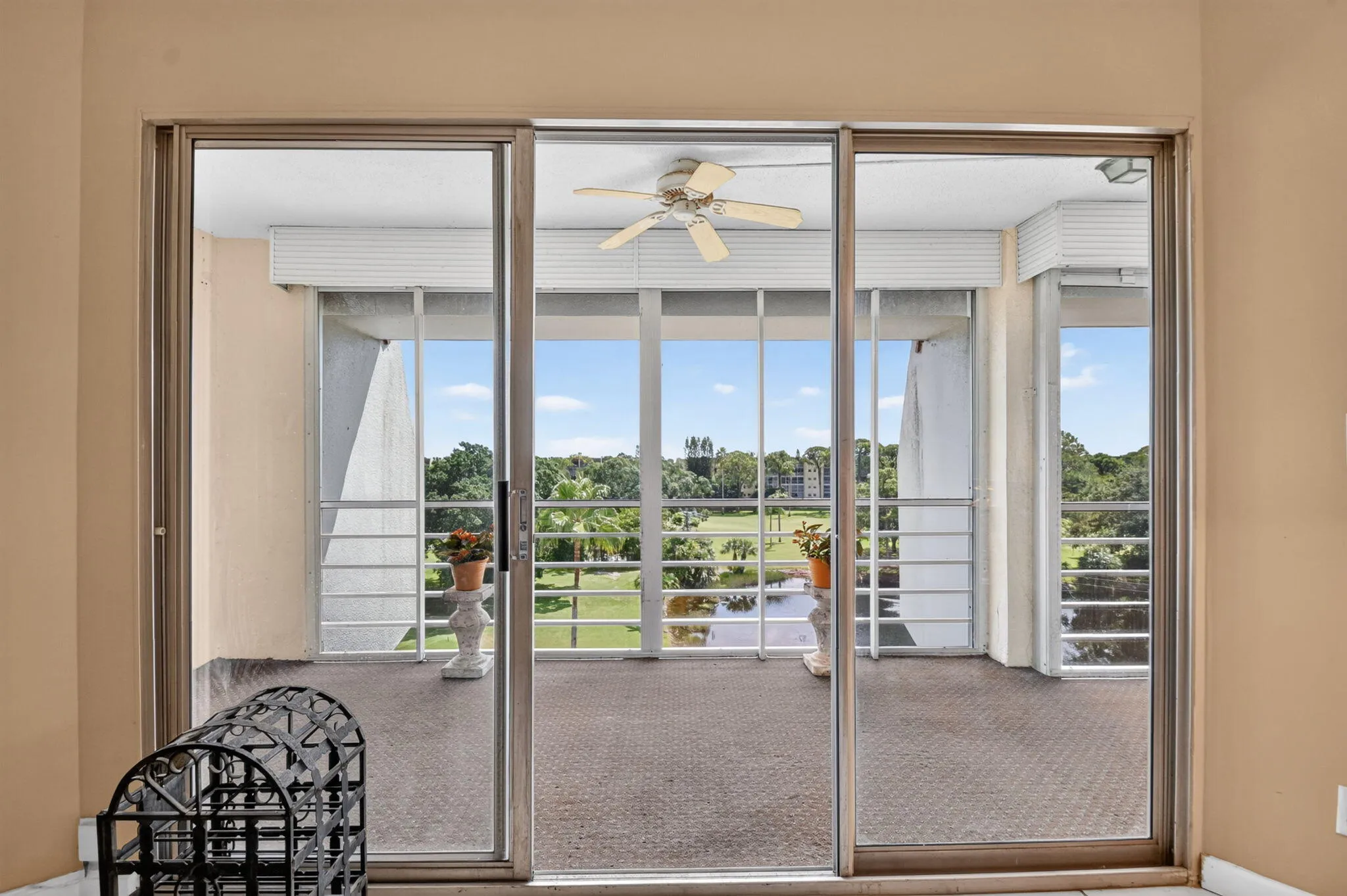 Sliding glass doors opening to a screened balcony, featuring a ceiling fan, and a neutral-toned wall finish