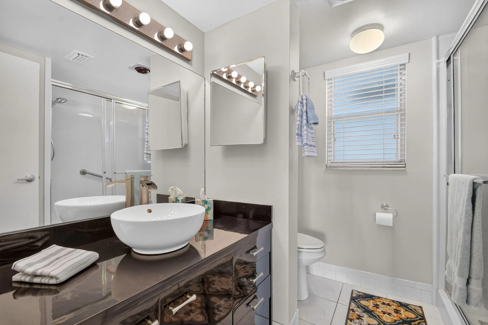 Vanity with vessel sink, brushed gold-finish faucet, and integrated mirror