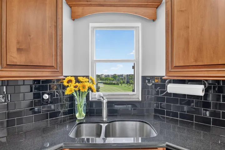 Dual basin stainless steel sink set within granite countertops. Window with view of manicured green spaces.