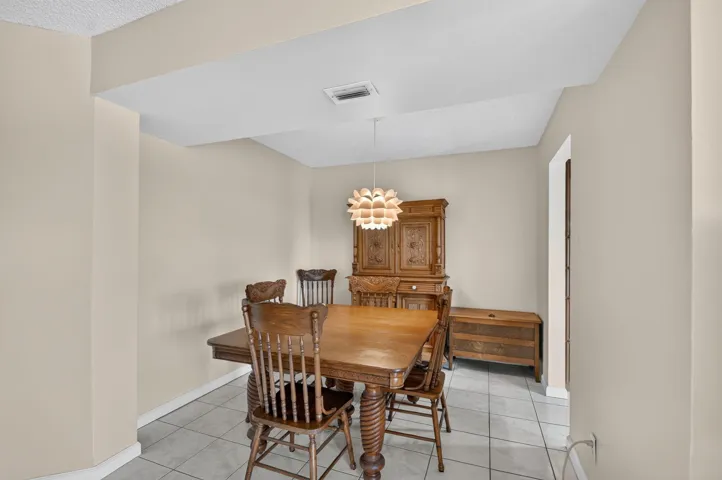 Recessed ceiling with a central light fixture, neutral wall tones, and tile flooring