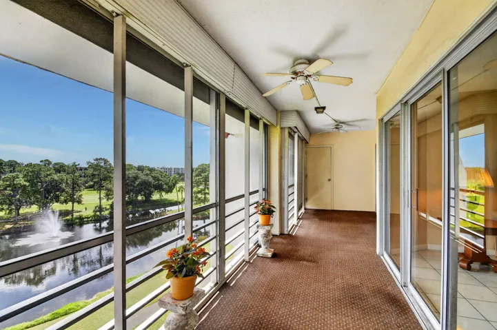 Enclosed balcony with large sliding glass panels, Concrete flooring, g two ceiling fans